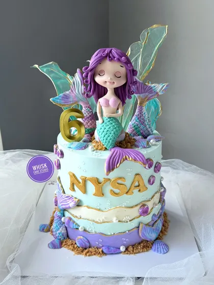 The prettiest mermaid cake is here. This all-edible, non-fondant cake is decorated with a beautiful mermaid figurine and iridescent, handcrafted tails.