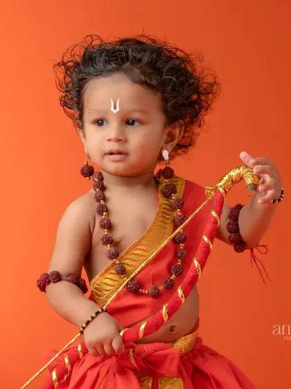 A beautiful close-up portrait of the baby as Rama. The focus is on the child's innocent face, traditional tilak, and rudraksha jewelry.