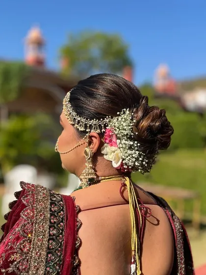 The charm of a floral wedding bun is unbeatable. This side-swept bun is adorned with baby's breath and pink flowers, creating a soft and romantic look.