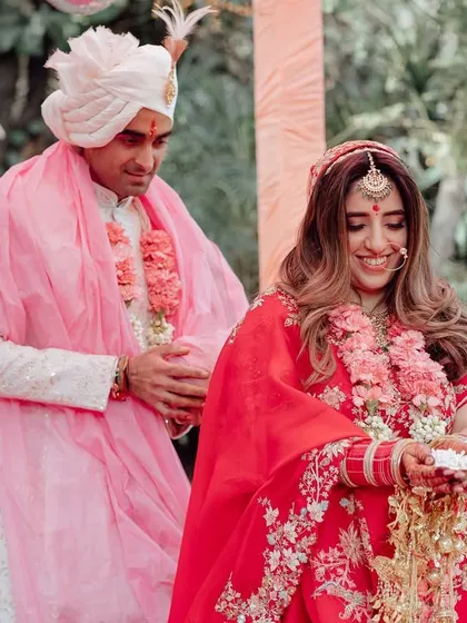 A sweet, candid moment during a Hindu wedding ceremony, capturing the couple's smiles and the traditional rituals.