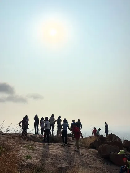 A silhouette of a group of young trekkers on a rocky outcrop against the bright sun. This photo captures the spirit of adventure and accomplishment that defines our youth camps.