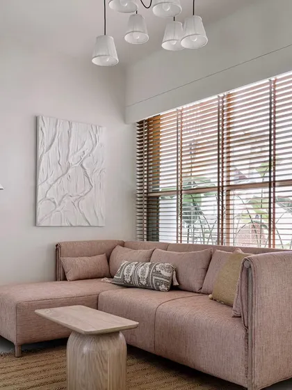 The guest bedroom is a calming space with a dusty pink sofa, natural fiber rug, and large windows that let in plenty of light.