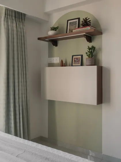 A space-saving floating cabinet is set within a sage-green arched niche, creating a beautiful and functional corner in this bedroom.
