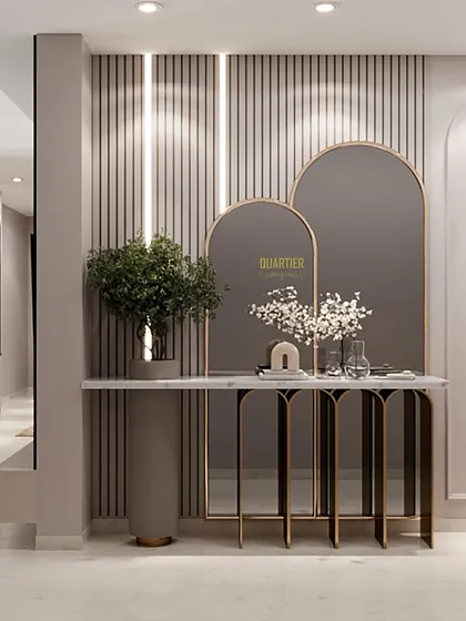 The foyer design for Apex D'Rio features a console table with a metallic frame and stone top, set against a wall of grey louvers. Arched mirrors and elegant wall lamps complete this sophisticated entryway.