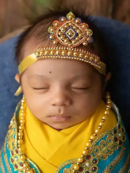 A detailed close-up of the baby's face and the beautiful, handcrafted crown for the Little Krishna theme.