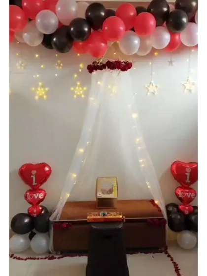 A full view of the romantic canopy setup. The combination of red, black, and white balloons, along with the glowing canopy and heart balloons, creates a classic and loving atmosphere.
