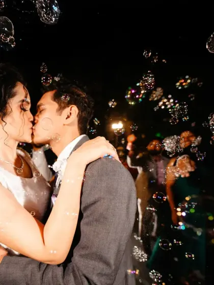 A magical moment captured in a flurry of bubbles. The way the light catches each bubble creates a dreamy, festive atmosphere around the couple's kiss.