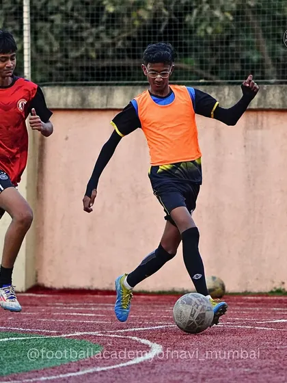 A player in an orange bib dribbles past a defender. These dynamic moments are where players get to showcase their skills.