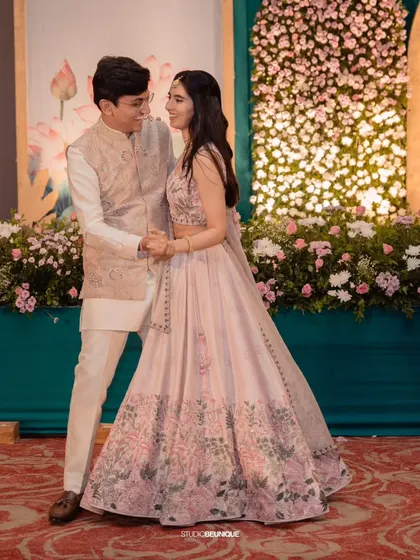 The couple shares a dance in front of a wall of pink and white flowers. I love creating these lush floral backdrops that add romance and beauty to any celebration.