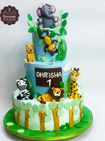A three-tier jungle animal theme cake for a first birthday. This design features adorable, hand-molded fondant animals like a lion, giraffe, and elephant, set against a vibrant jungle backdrop.
