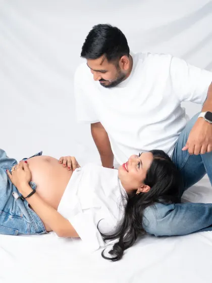 A sweet and relaxed moment. The mom-to-be lies comfortably with her head in her partner's lap, sharing a look of love and happiness.