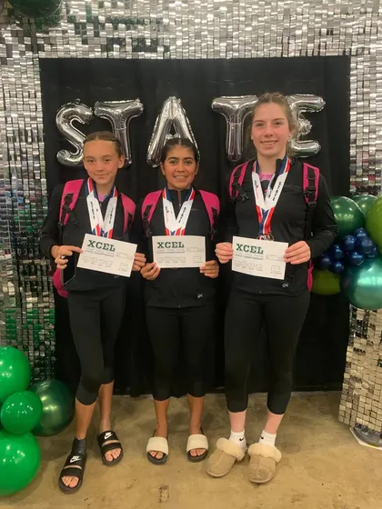 Three of our Xcel athletes proudly displaying their medals and certificates after competing at the State meet.