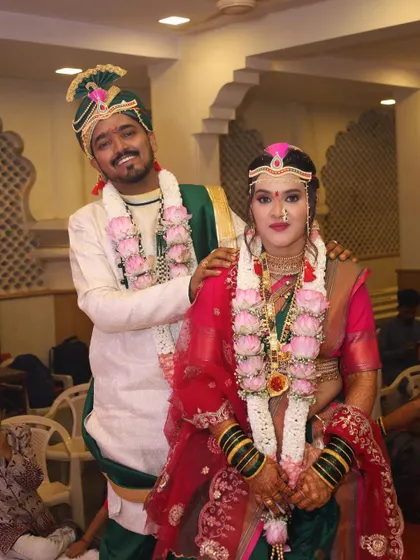A happy couple portrait. The bride is glowing in her green and pink Paithani, a classic choice for a Maharashtrian wedding ceremony.