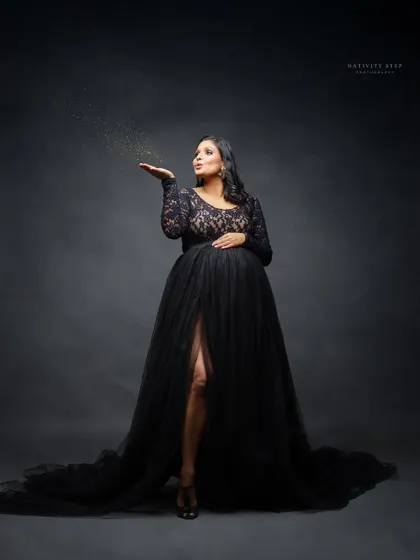 A magical moment as the mother-to-be blows golden glitter. This adds a touch of sparkle and celebration to the classic black gown portrait.