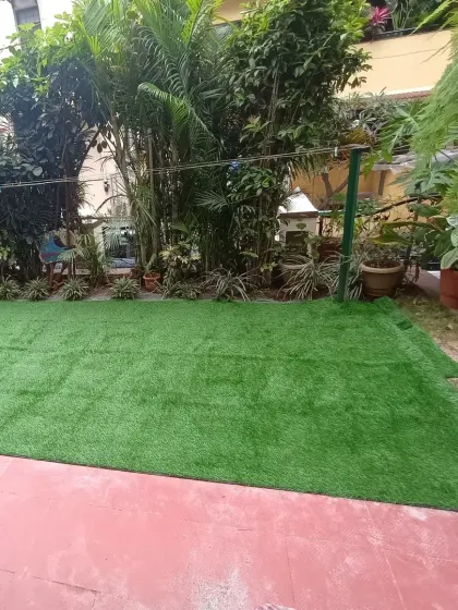 A finished patch of artificial lawn in a residential garden. This creates a perfect, low-maintenance spot for relaxing among the surrounding plants.