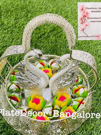 This silver basket with swan figurines holds an assortment of colorful pedas, a popular sweet for festive occasions.