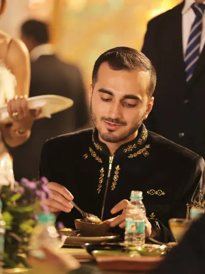 A guest dressed in traditional finery enjoys a dish from our menu. We take pride in catering to diverse celebrations, ensuring our food complements the occasion perfectly.