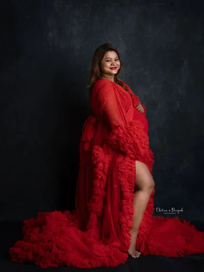 Confident and radiant in red. This classic pose with a side slit gown is a favorite for showing off both the baby bump and a bit of glamour.