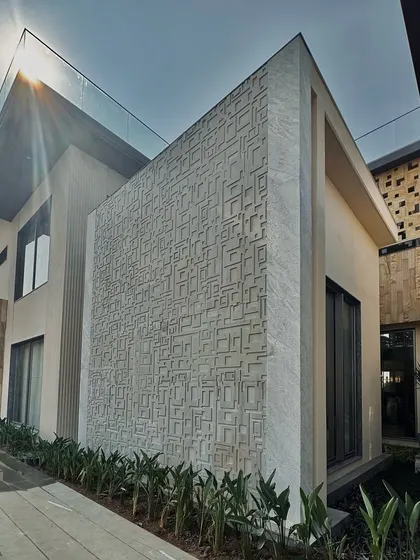 An intricately patterned feature wall on the exterior of the Chhattisgarh residence. This detail adds a layer of texture and artistry to the modern facade, playing with light and shadow throughout the day.