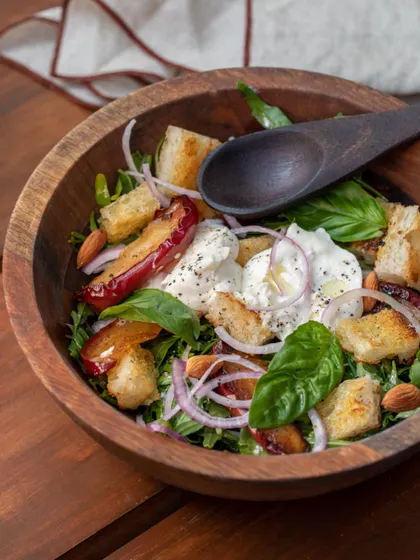 A beautiful wooden bowl filled with our Panzanella salad. It's a hearty and rustic dish that perfectly showcases our bread and cheese.