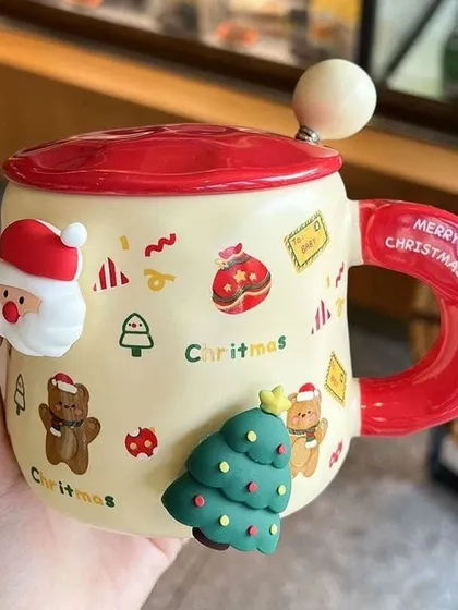 This adorable Christmas-themed mug comes with a lid and spoon. It's decorated with cute 3D figures of Santa, a Christmas tree, and a teddy bear.