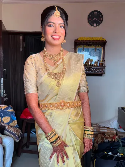 A full-length view of the bride in her elegant off-white and gold Kanjivaram saree, complete with a traditional waist belt (vaddanam).