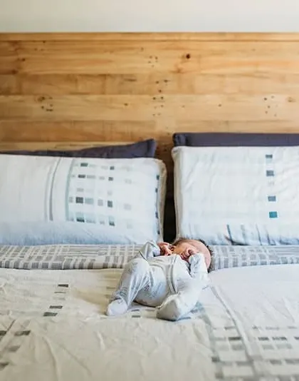 A wide shot showing just how small a newborn looks on a big bed. This perspective helps tell the story of their first days at home.