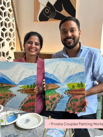 A couple from a private painting workshop in Delhi, proudly displaying their finished mountain landscape paintings.