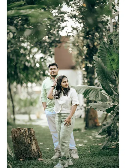 A stylish couple posing in a lush green garden, a perfect shot for a modern pre-wedding announcement.
