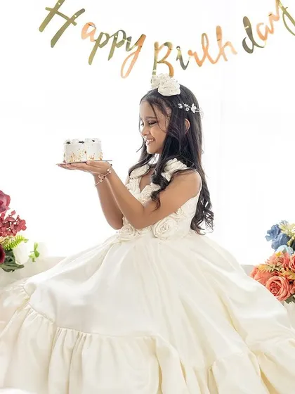 A classic birthday pose with a mini cake. The soft lighting and floral props enhance the elegance of this seventh birthday session.