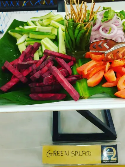 A classic green salad platter with sliced cucumbers, tomatoes, beetroot, and onions, served with pickled chilies.