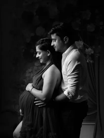 A soft and intimate black and white portrait of an expecting couple, highlighting the beautiful silhouette of the baby bump.