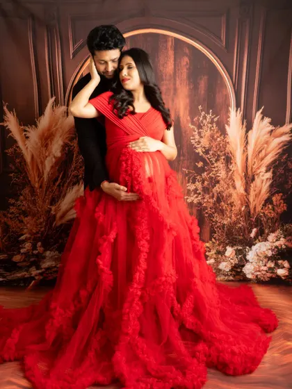 A loving embrace in front of a rustic pampas grass backdrop. The rich red of the gown adds a touch of passion and drama to this couple's portrait.