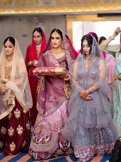 The bride's entrance during the Anand Karaj ceremony, surrounded by her bridesmaids. A moment filled with anticipation and emotion.
