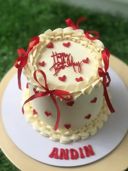 A sweet vintage-style cake with red hearts and delicate red ribbon bows.
