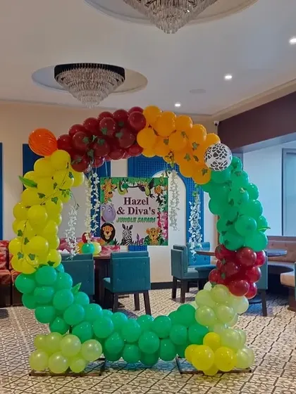 A jungle-themed circular balloon arch used as a photo booth or cake-cutting backdrop inside the venue.