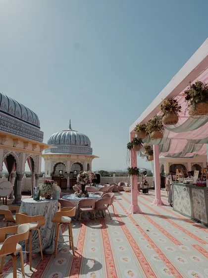 A view of the rooftop venue, showing the pastel-colored canopy and dining setup. The open-air setting at The Leela Palace Jaipur provides a beautiful backdrop for the romantic decor.