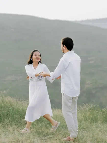 A fun and dynamic shot of the couple dancing and twirling in a vast green field.