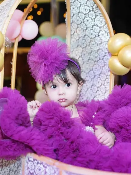 A beautiful, classic portrait of the birthday girl. Dressed in a stunning purple ruffled dress, she looks like a little doll, creating a timeless memory of her special day.
