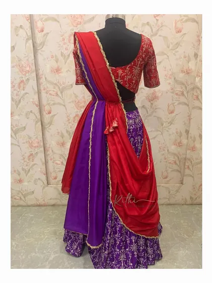 A vibrant half saree in red and purple, perfect for a Sangeet or pre-wedding event. The look is completed with a custom embroidered blouse and waistband.