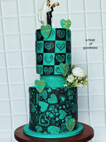This angle highlights the contrast between the checkered heart pattern and the free-form heart collage on the bottom tier. The addition of 3D hearts with gold detailing adds another layer of texture and sophistication.