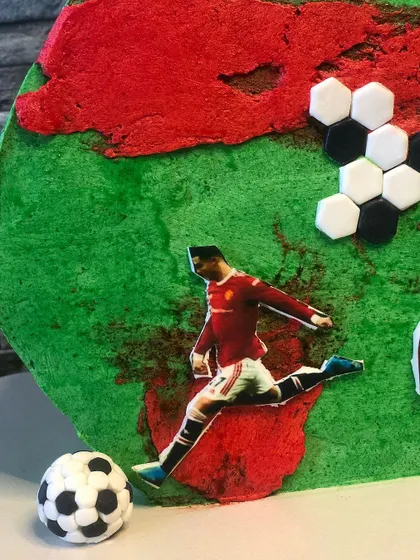 A close-up on the details of the football cake. You can see the edible image of Ronaldo in action, the hand-placed hexagonal fondant pieces forming a soccer ball pattern, and a miniature fondant ball.