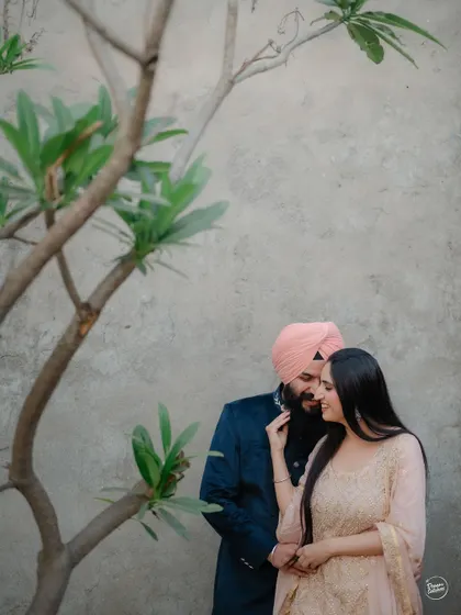 An intimate moment shared between a couple, framed by the delicate branches of a tree. This composition adds a touch of nature and artistry to their pre-wedding session in Amritsar.