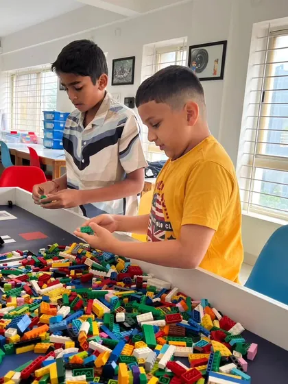 Two young builders are completely absorbed in constructing with a large pile of LEGO bricks. This foundational and fun activity is the first step in creating the custom elements needed for the WRO challenges.
