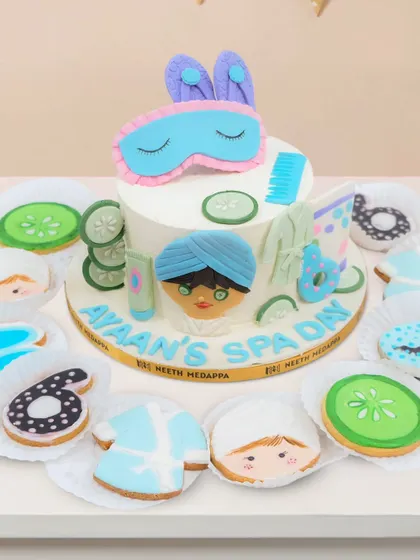 Here is a closer look at the spa day cake and cookies. The cake for "Ayaan's Spa Day" is surrounded by cookies shaped like face masks, cucumbers, and little bathrobes.