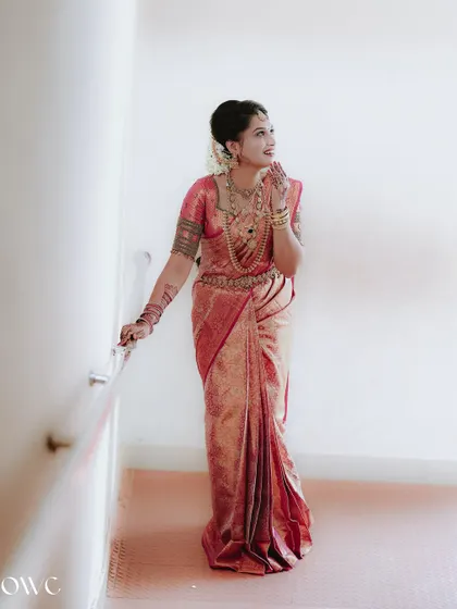 An elegant full-length portrait of the bride against a clean white wall, highlighting the beauty of her saree.