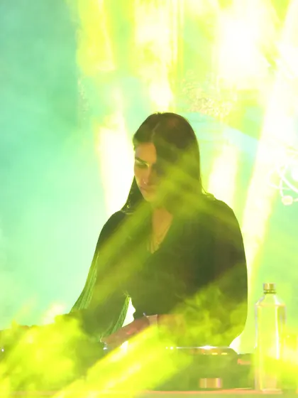 A dramatic shot of me at the console at Molecule Meerut, surrounded by green light and smoke. The lighting and effects are a huge part of the sensory experience I create.