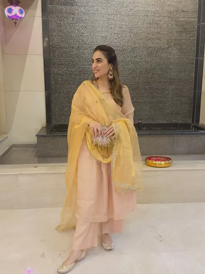 A peach-colored suit with a yellow organza dupatta. This is a soft, elegant look for a festive gathering.