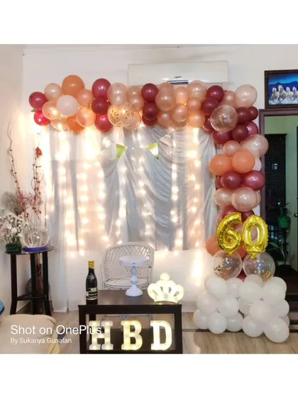 Celebrating a 60th birthday at home with elegance. This setup features a beautiful balloon arch in chrome and pastel colors, a '60' foil balloon, and marquee letters, proving that home parties can be just as grand.
