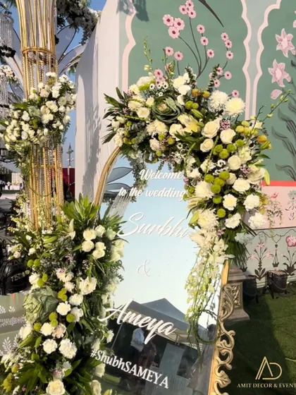 A floral-framed welcome mirror, reflecting the grand mandap in the background. It's a beautiful way to welcome guests while giving them a peek of the decor to come.